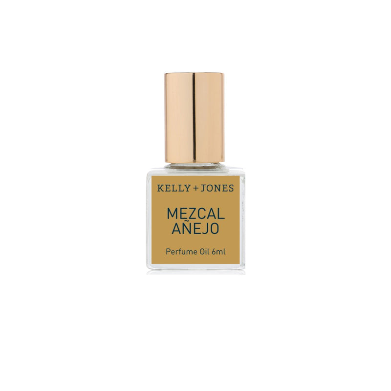 A bottle of Kelly + Jones MEZCAL AÑEJO Perfume Oil Roll-On with a gold-colored label and cap, set against a white background.