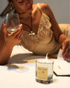 Woman sipping on wine and reading while burning a scented Mezcal Blanca candle