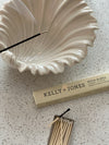 White shell-shaped incense burner with a matchbox and matches on a speckled surface, featuring Kelly + Jones Mezcal Blanca Incense