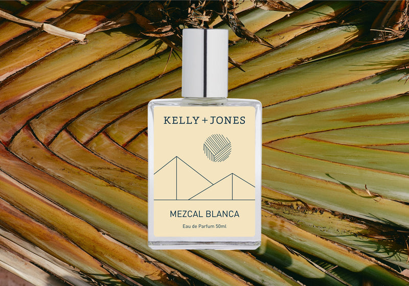 A bottle of Mezcal Blanca Eau de Parfum Spray with a tropical palm leaf