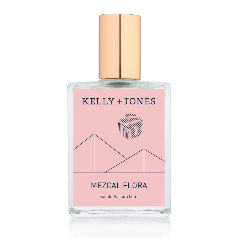 A bottle of Kelly + Jones Mezcal Flora Eau de Parfum Spray with a pink label and a gold cap.