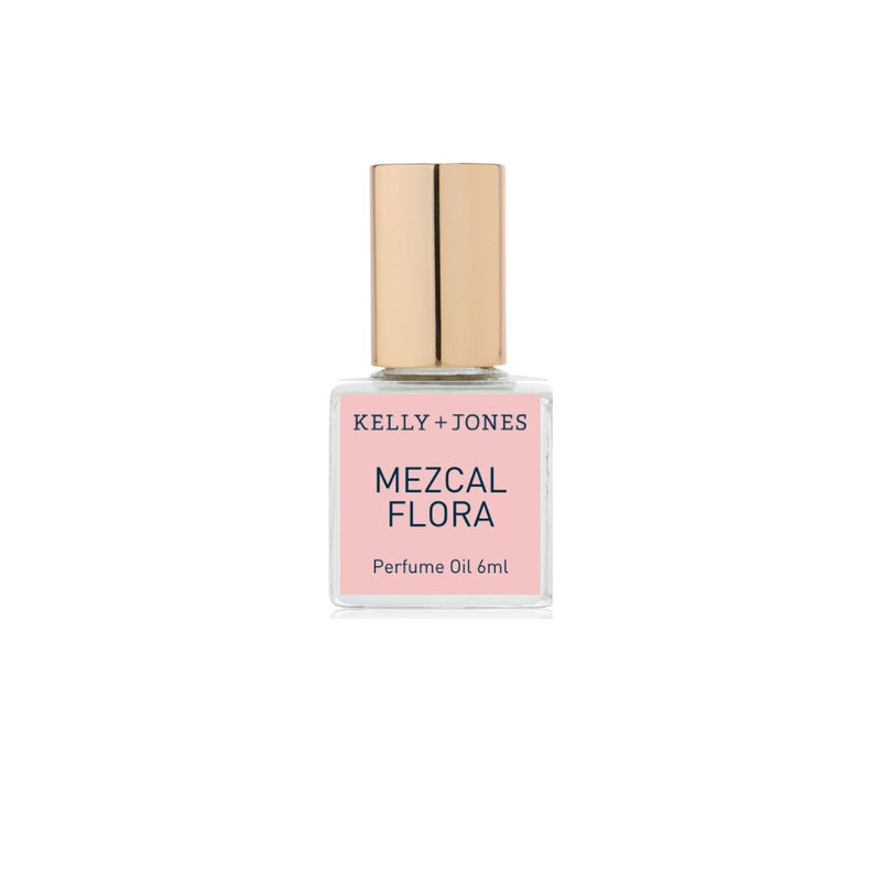 A bottle of Kelly + Jones Mezcal Flora Perfume Oil with a pink label and a gold cap.