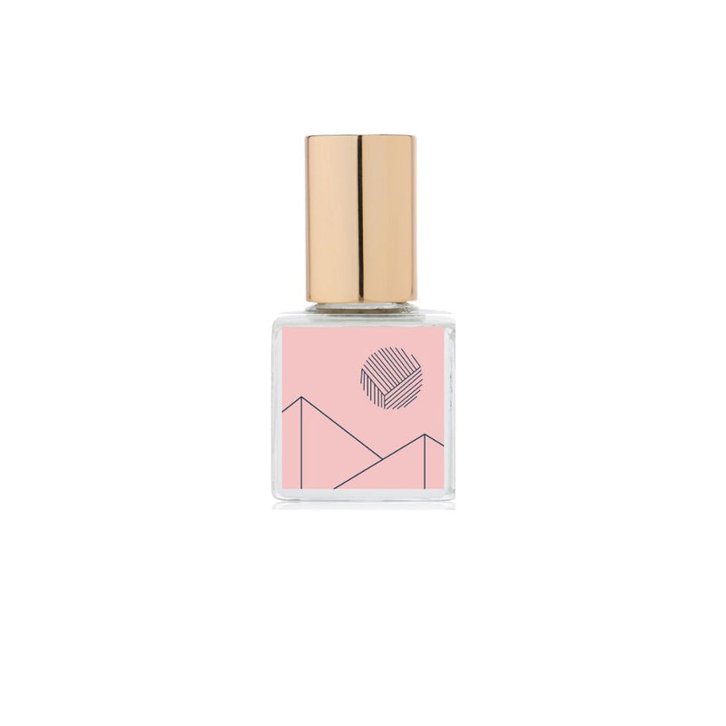 A bottle of Kelly + Jones Mezcal Flora Perfume Oil with a pink label and a gold cap.
