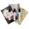 Three sample spray vials labeled Añejo, Flora, and Azul, placed on top of postcards with floral and natural imagery.