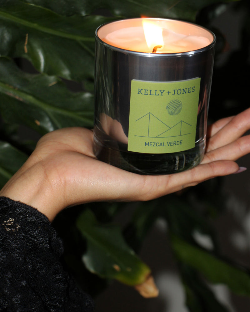 Woman's palm holding a Mezcal Verde scented candle in a jungle setting